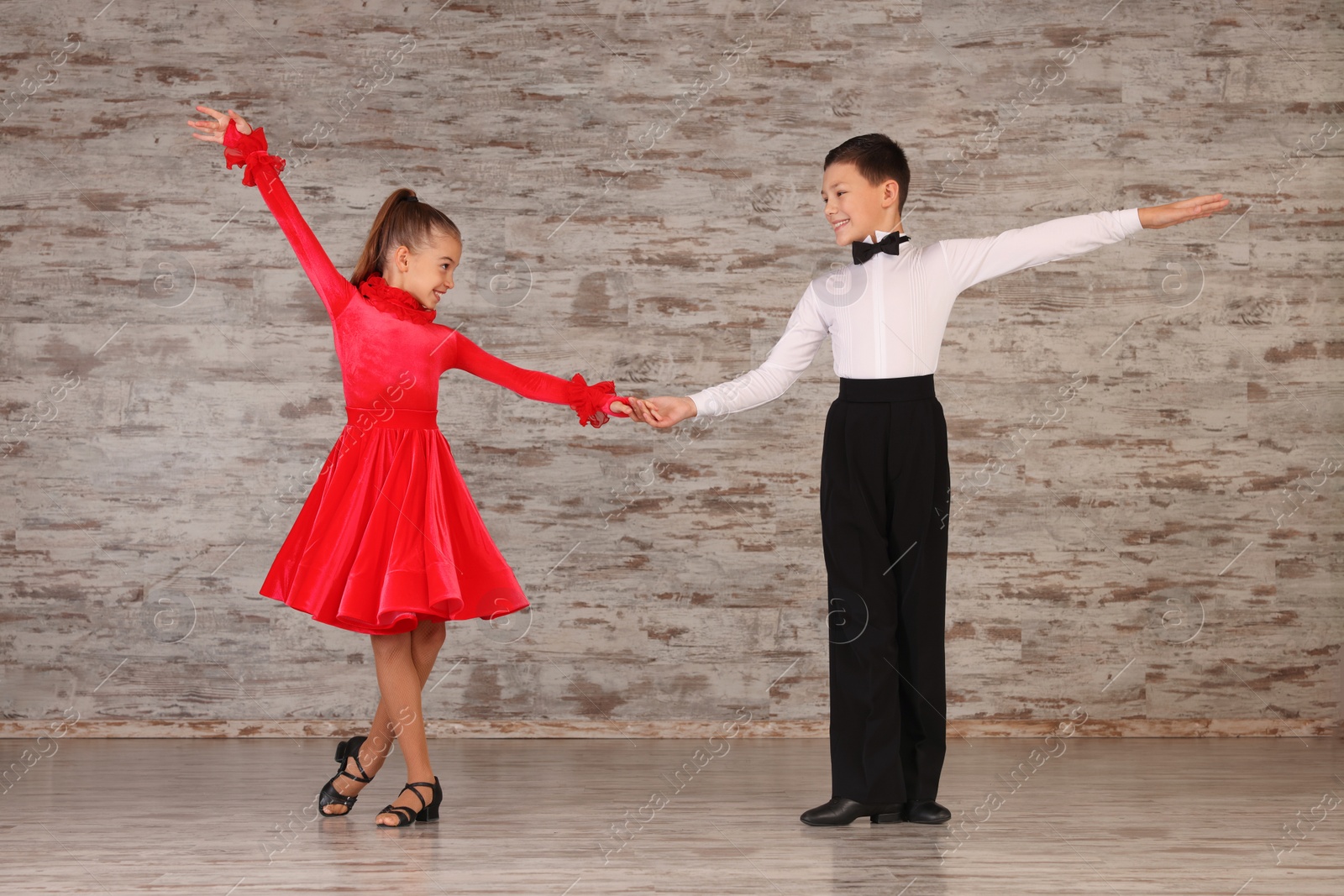 Photo of Beautifully dressed couple of kids dancing together in studio