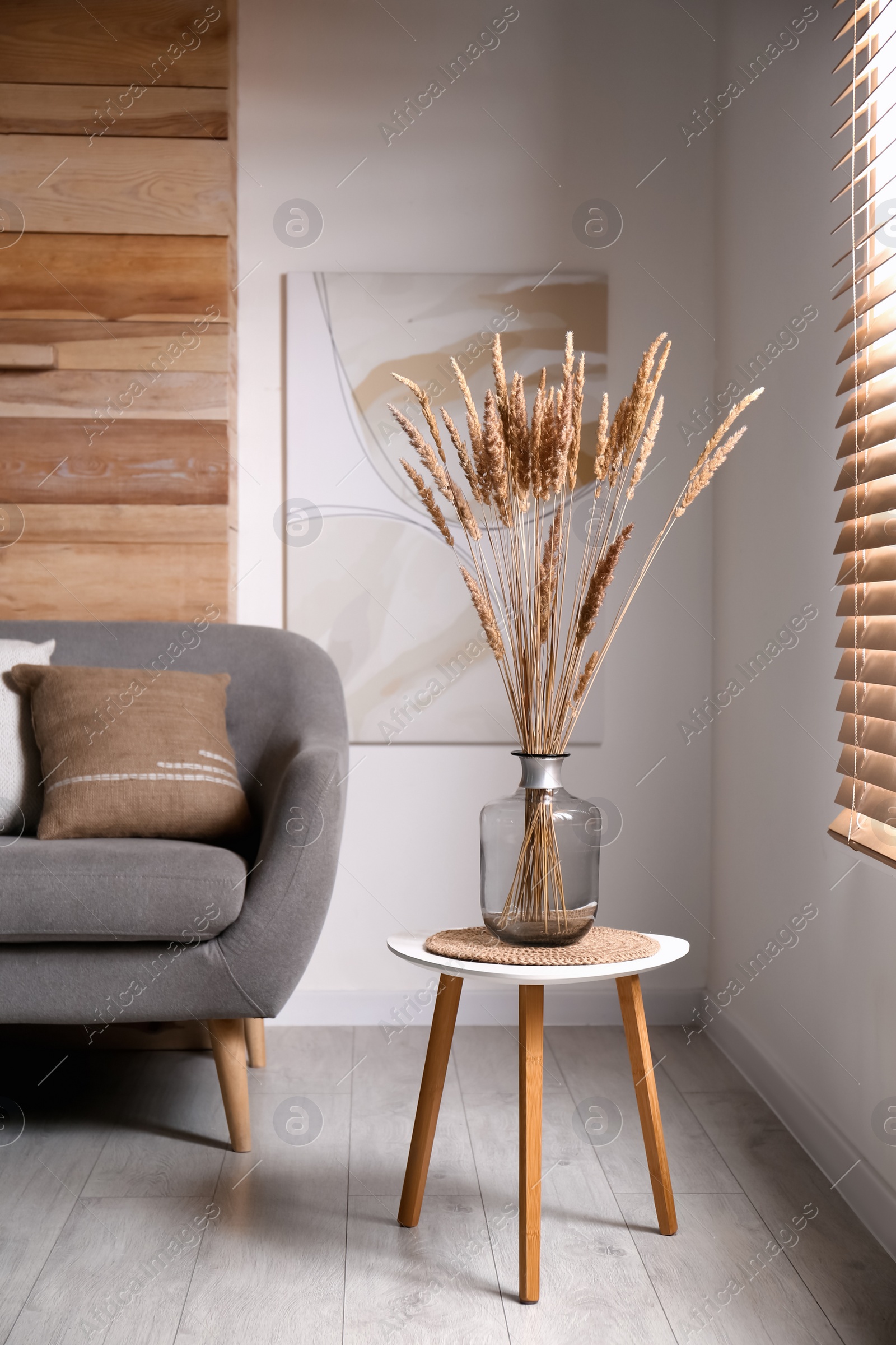 Photo of Vase with decorative dried plants on table in living room. Interior design