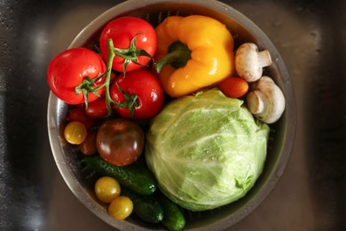 Photo of Different wet vegetables in metal colander inside sink, top view