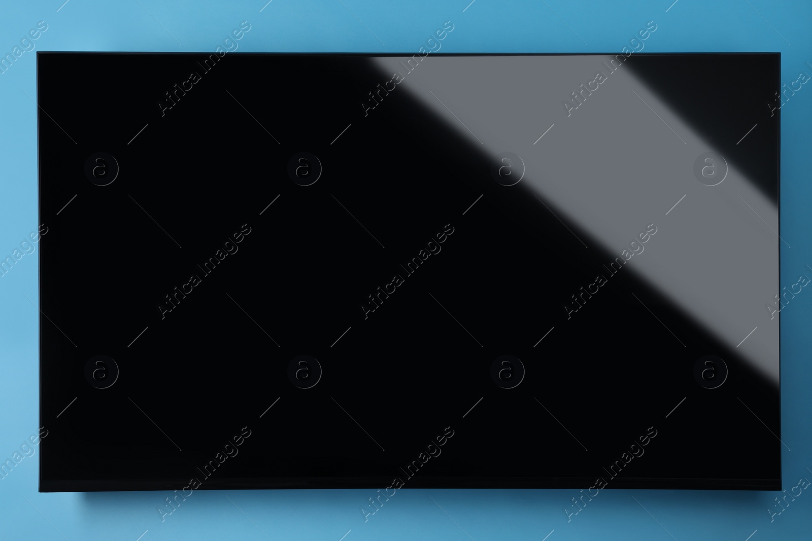 Photo of Modern TV with blank wide screen on light blue background