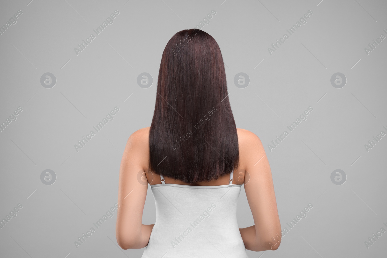 Photo of Woman with healthy hair on grey background, back view