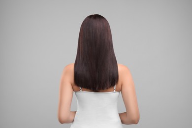 Woman with healthy hair on grey background, back view