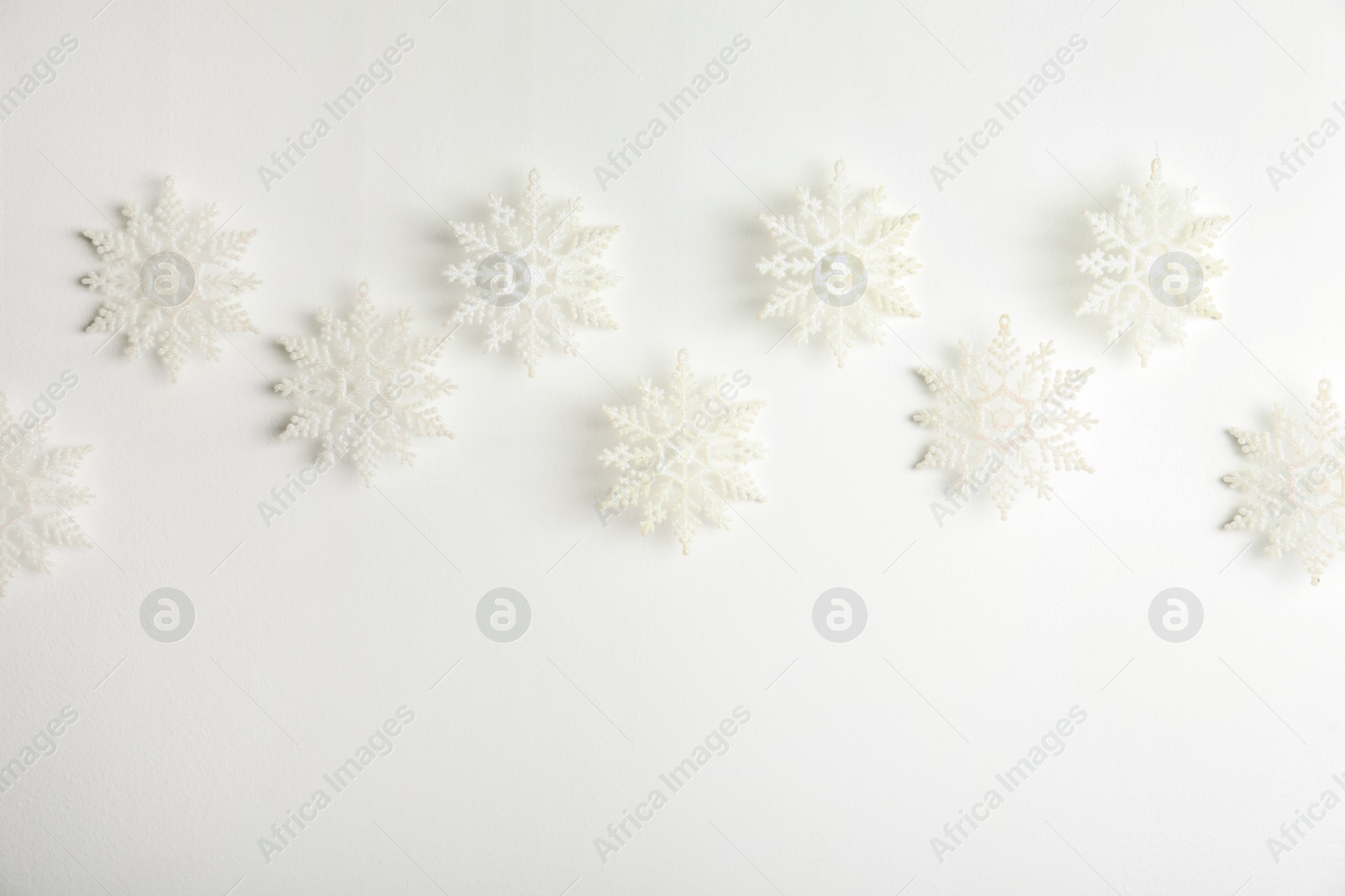 Photo of Beautiful decorative snowflakes hanging on white background, space for text