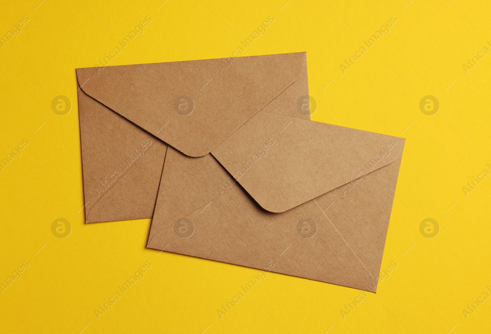 Photo of Envelopes made of parchment paper on yellow background, flat lay