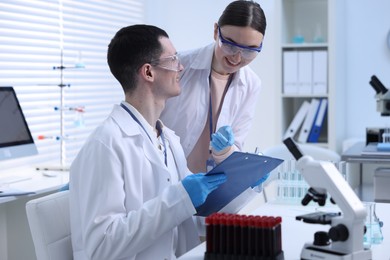 Scientists working with laboratory test form at table indoors