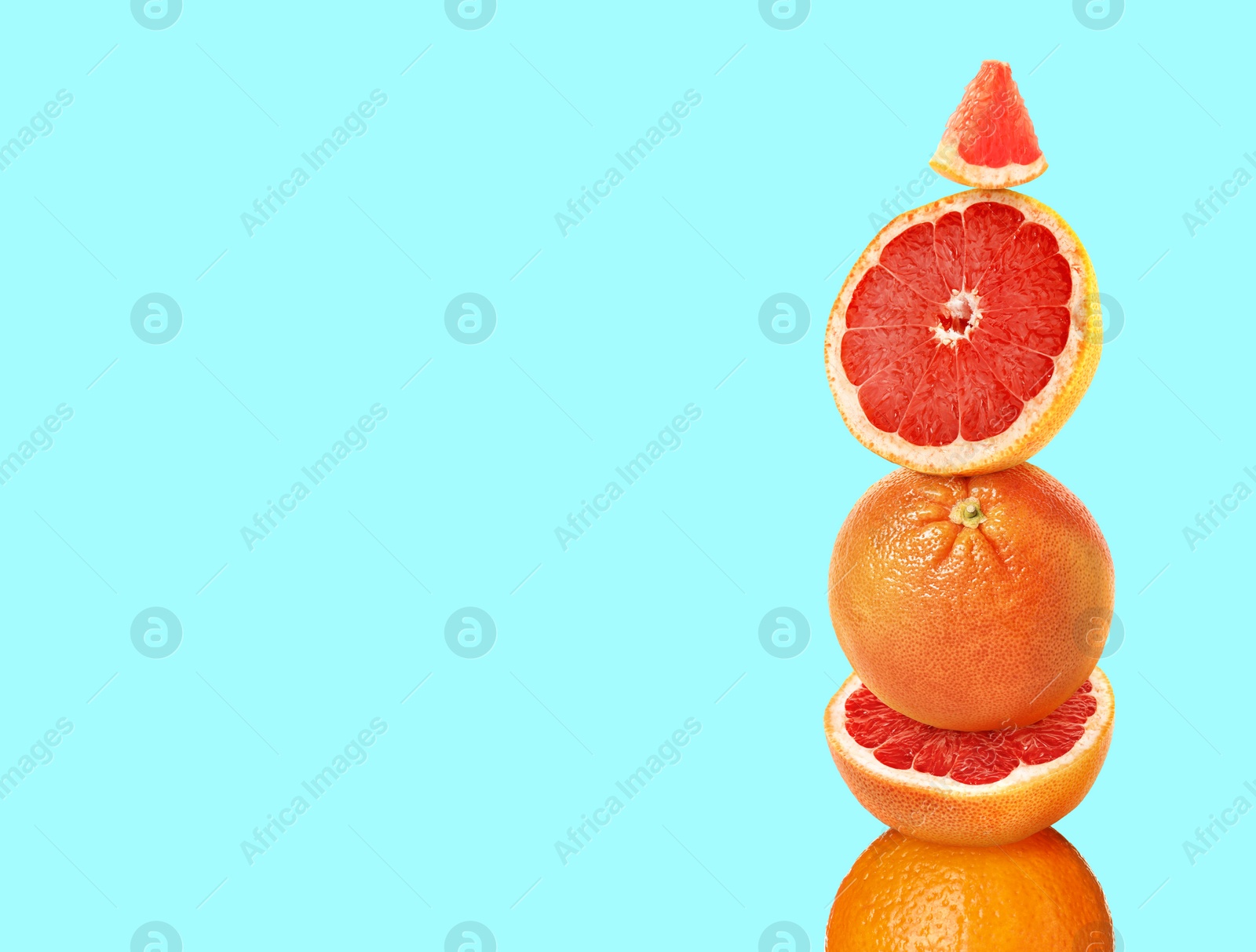 Image of Stacked cut and whole grapefruits on light blue background, space for text