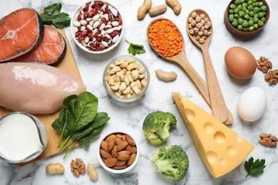 Photo of Products rich in protein on white marble table, flat lay