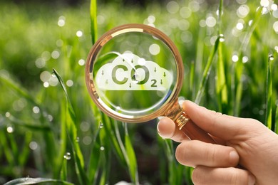 Image of Reduce CO2 emissions. Woman demonstrating CO2 inscription through magnifying glass outdoors, closeup