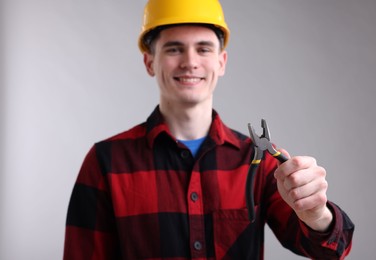 Photo of Young man holding pliers on grey background, selective focus