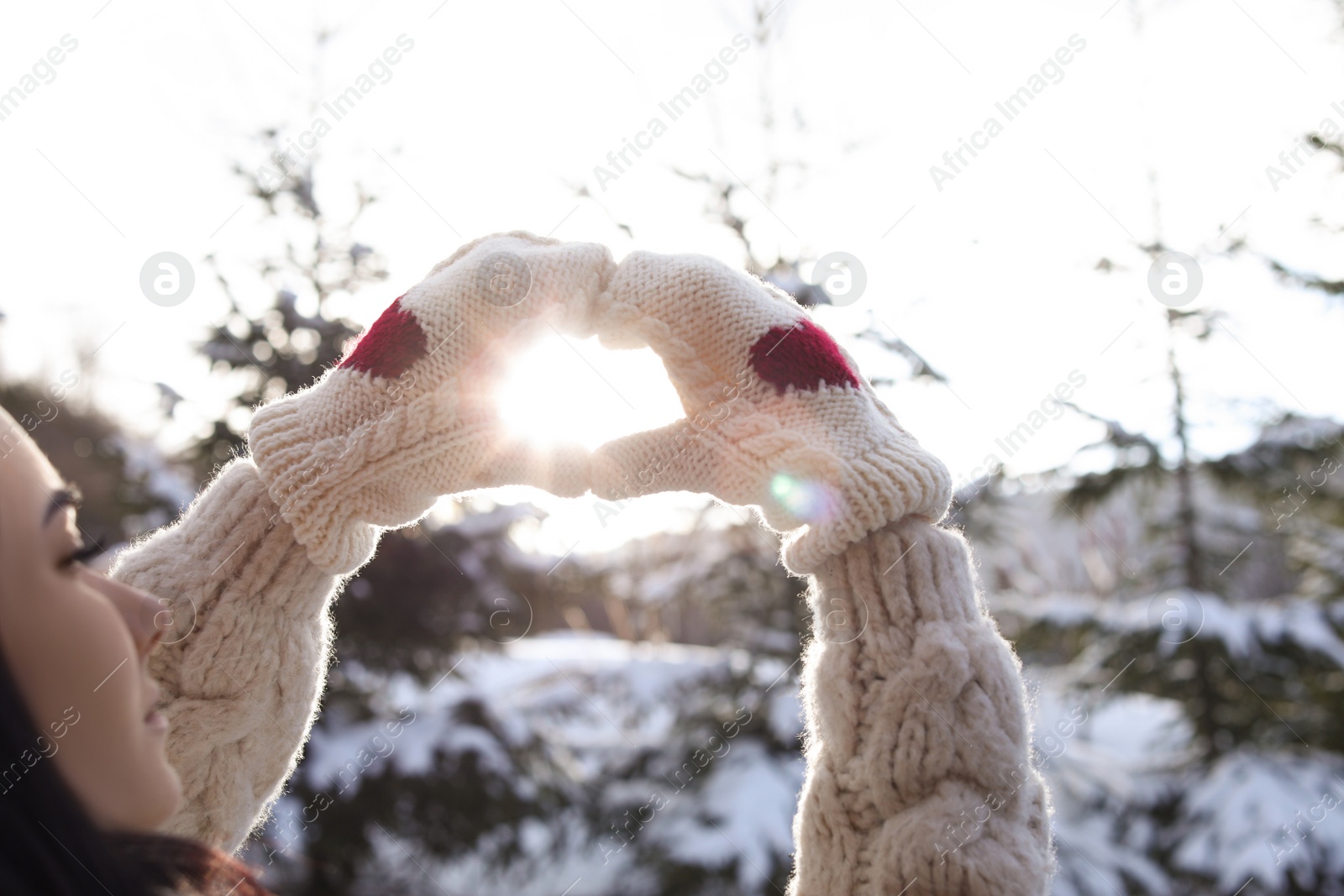 Photo of Young woman making heart with hands outdoors, closeup. Winter vacation