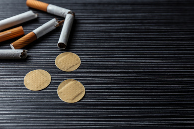 Photo of Nicotine patches and broken cigarettes on black table. Space for text