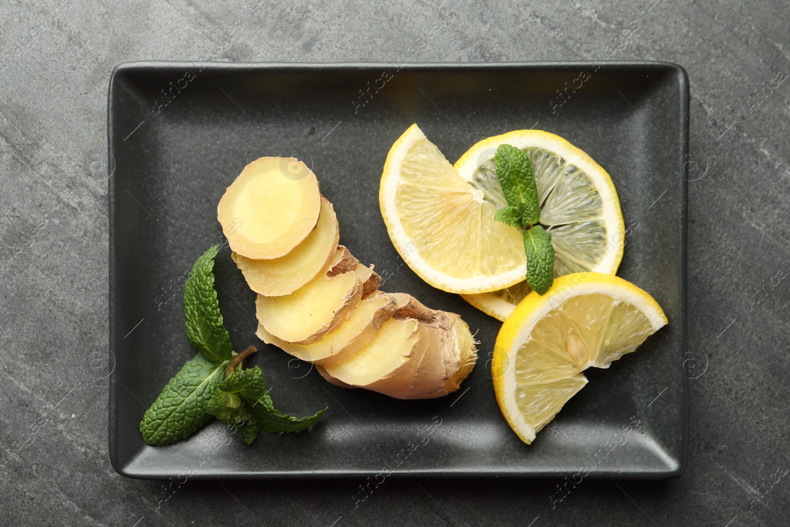 Photo of Fresh lemon, ginger and mint on grey table, top view