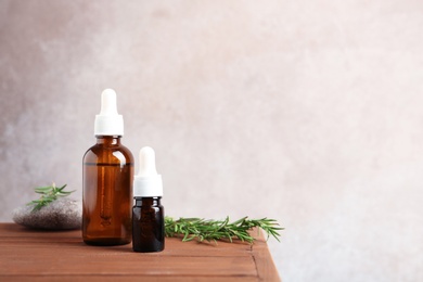 Bottles with fresh rosemary oil on table