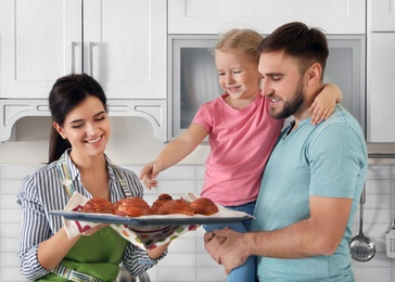 Photo of Beautiful woman treating her family with freshly oven baked buns in kitchen