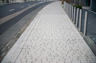 Photo of Sidewalk path near road on city street. Footpath covering