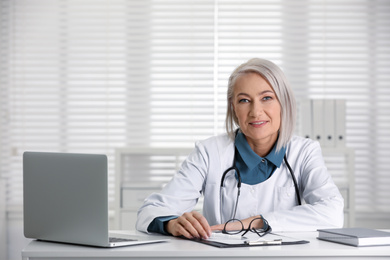 Portrait of mature female doctor in white coat at workplace