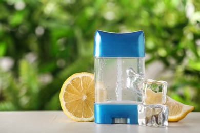 Photo of Deodorant container, ice cubes and citrus on white wooden table against blurred background