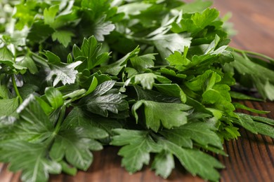 Photo of Bunch of fresh green parsley leaves on wooden table, closeup