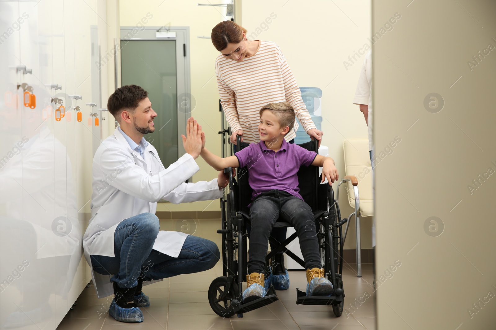 Photo of Doctor with woman and her child in wheelchair at hospital