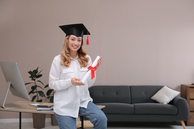 Photo of Happy student with graduation hat and diploma at workplace in office