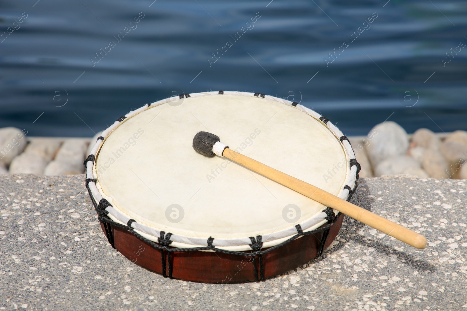 Photo of Drum and drumstick near sea. Percussion musical instrument