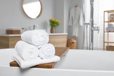 Photo of Rolled white towels on tub in bathroom. Space for text