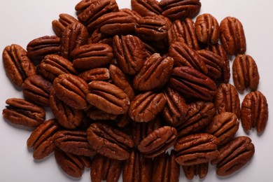 Photo of Pile of delicious fresh pecan nuts on white background, top view