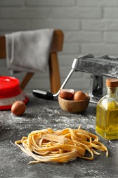 Homemade pasta, maker and ingredients on dark grey table