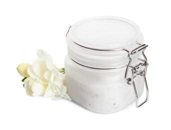 Photo of Jar of exfoliating salt scrub and freesia flowers on white background