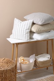 Photo of Soft pillows and laundry baskets near beige wall indoors