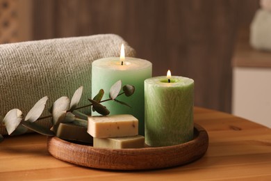 Spa composition. Burning candles, soap, towel and eucalyptus branch on wooden table