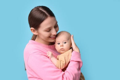 Happy mother with her cute baby on light blue background