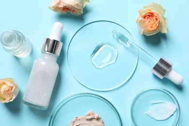 Photo of Bottle of cosmetic serum, flowers and petri dishes with samples on light blue background, flat lay