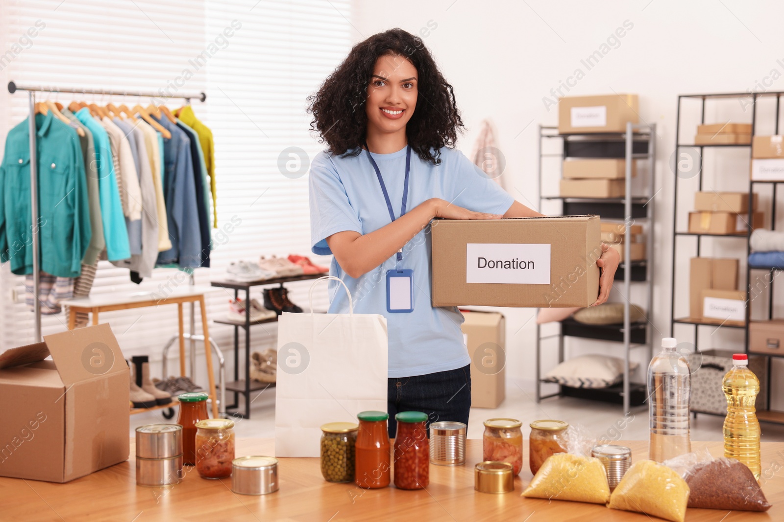 Photo of Volunteer with donation box and food products at table in warehouse