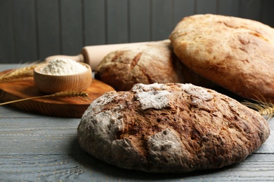 Photo of Loaf of delicious fresh bread on grey wooden table