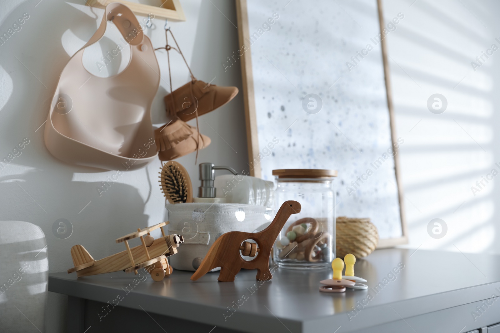Photo of Wooden toys and pacifiers on grey table in child room