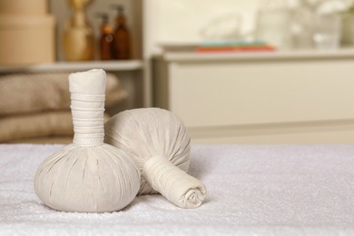 Photo of Herbal massage bags on bath towel indoors, space for text. Spa procedure