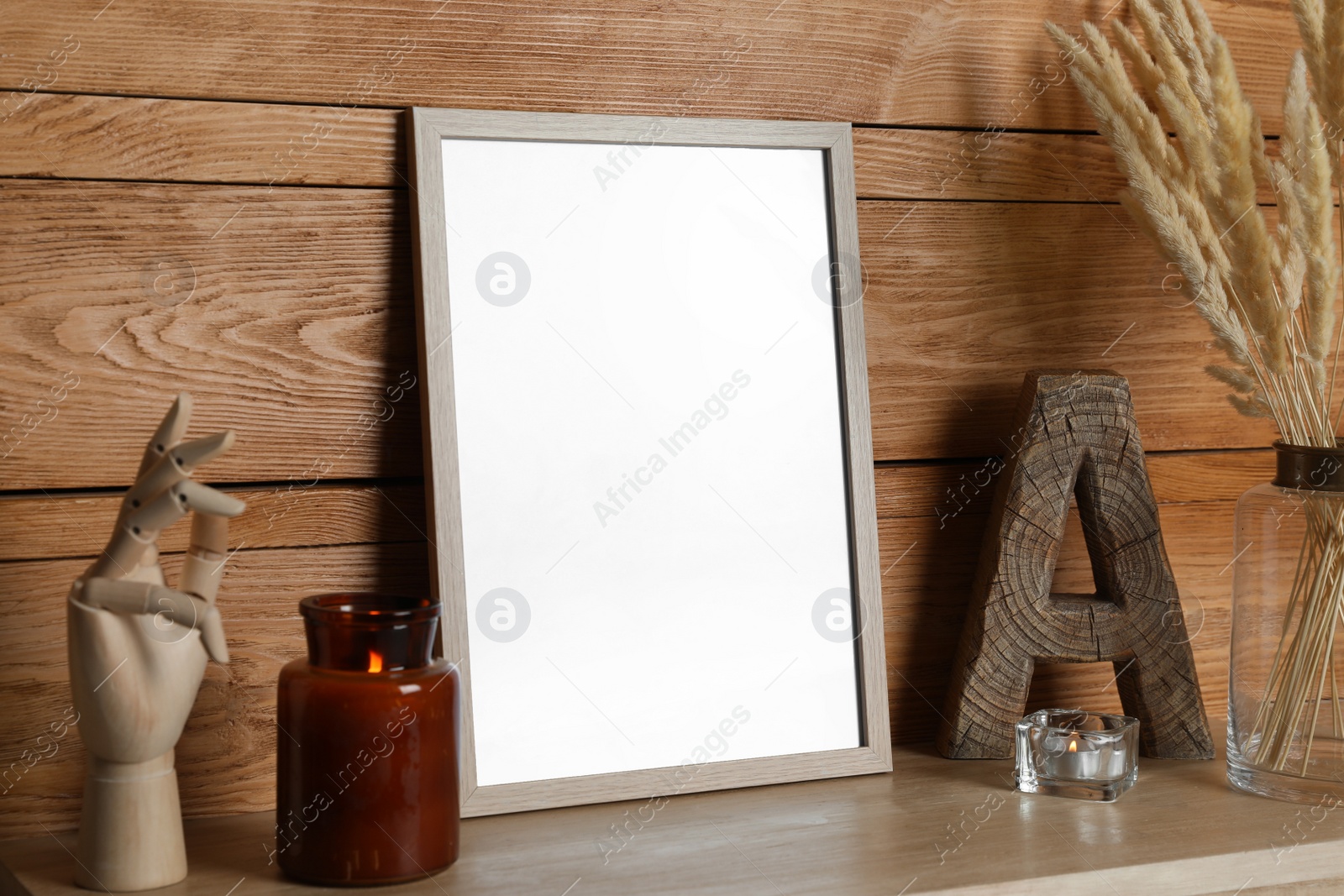 Photo of Empty frame with other decor on table near wooden wall. Mockup for design