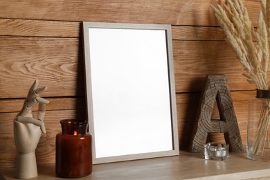 Photo of Empty frame with other decor on table near wooden wall. Mockup for design