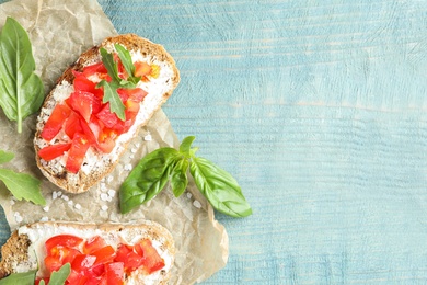 Photo of Delicious tomato bruschettas on light blue wooden background, flat lay. Space for text