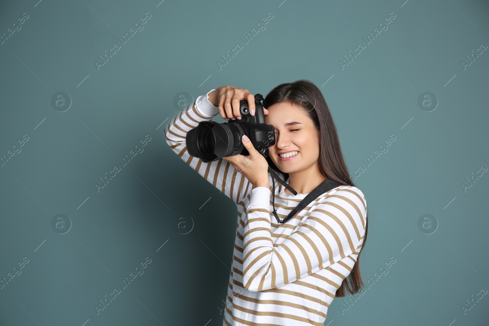 Photo of Young female photographer with camera on grey background