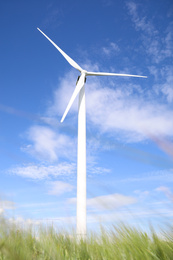Photo of Wind turbine in field on sunny day, low angle view. Alternative energy source