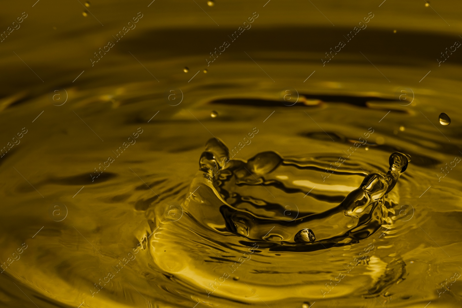 Image of Splash of golden oily liquid with drops as background, closeup