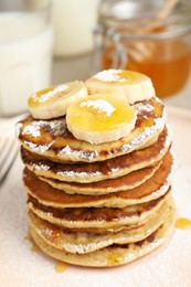 Photo of Banana pancakes with honey and powdered sugar on plate, closeup