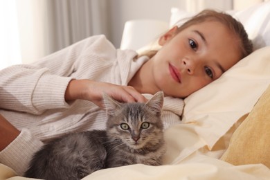 Photo of Cute little child with kitten at home, focus on pet