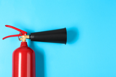 Fire extinguisher on light blue background, top view. Space for text