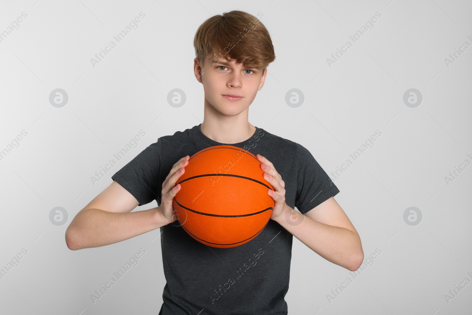 Photo of Teenage boy with basketball ball on light grey background