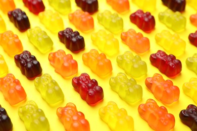 Photo of Delicious gummy bear candies on yellow background, closeup