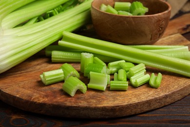 Photo of Board with fresh cut celery stalks on wooden table, closeup