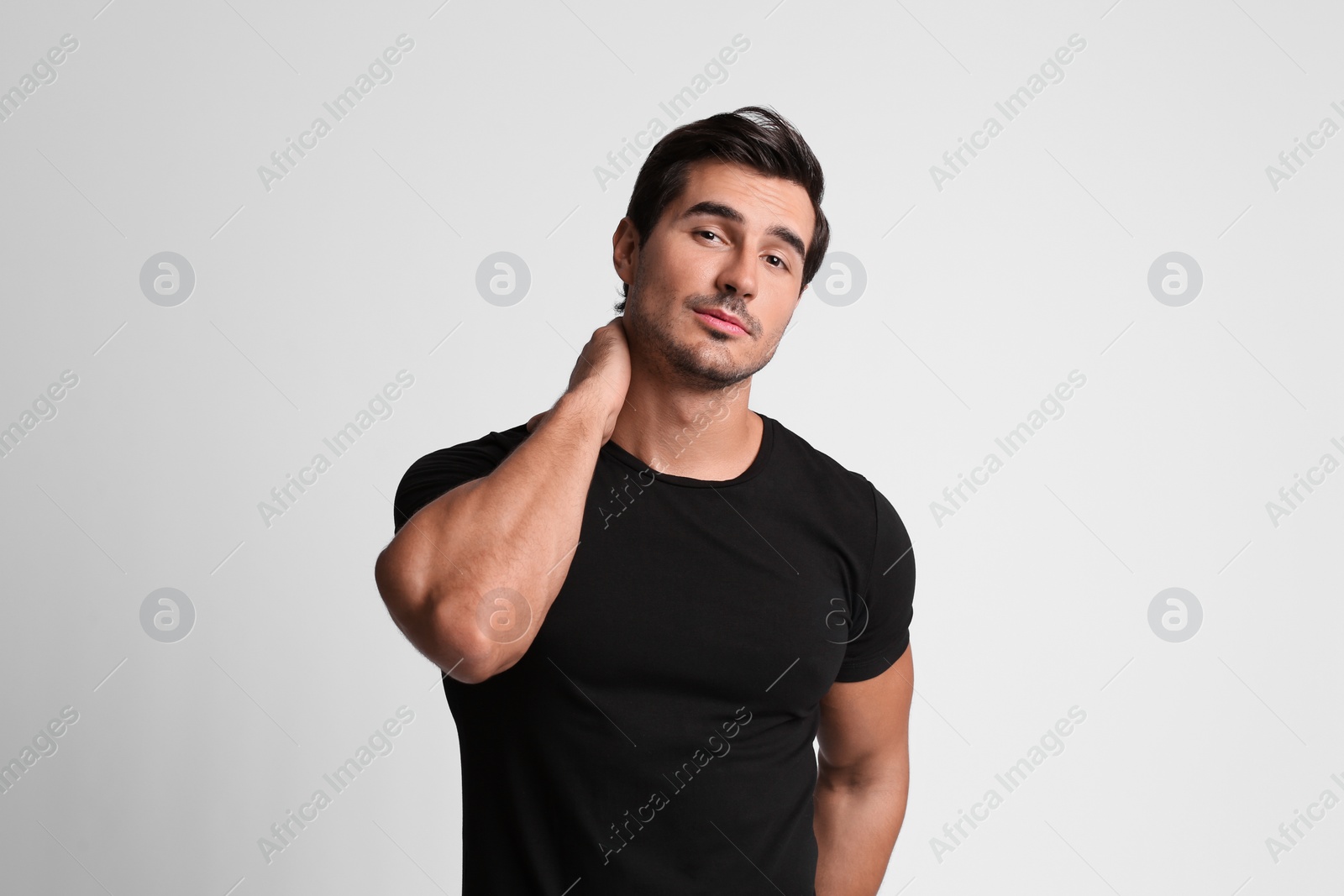 Photo of Portrait of handsome young man in black t-shirt on grey background